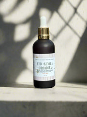 CBD + Kenzai Broadleaf bottle on a light surface with a shadowy background